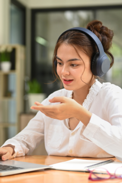 A young person on a video call at a laptop, wearing headphones. 