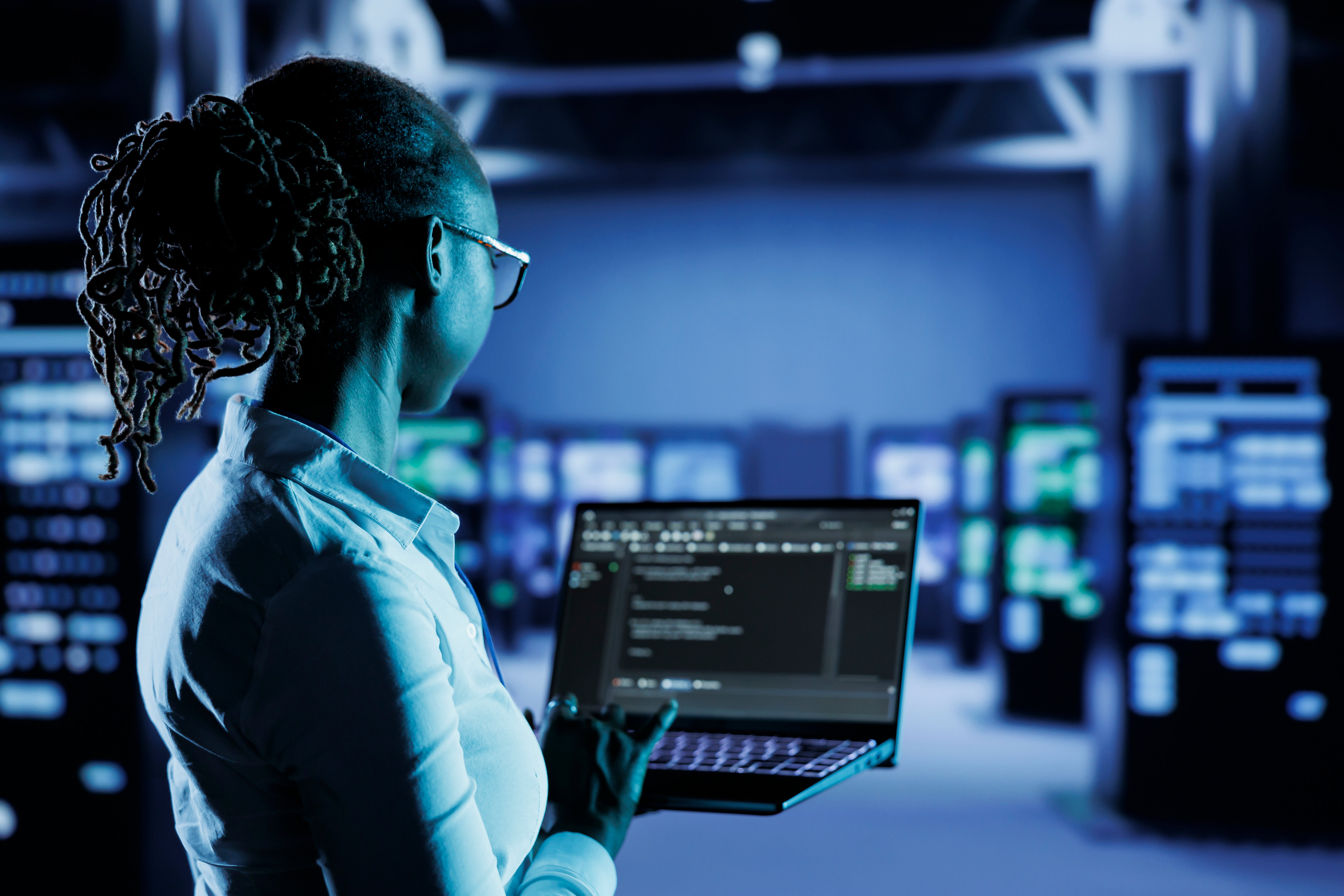 Cybersecurity professional working on a laptop in a data centre.