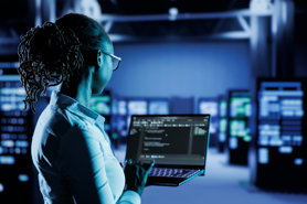 Cybersecurity professional working on a laptop in a data centre.