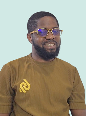 A man with a beard wearing glasses and a brown shirt with a yellow logo smiles against a light blue background.