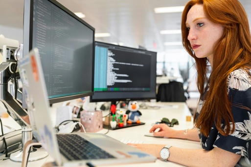 A Software Developer working across multiple screens in an office environment