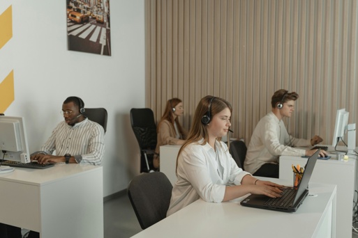 Office staff wearing headsets responding to calls and verifying information at their work stations.