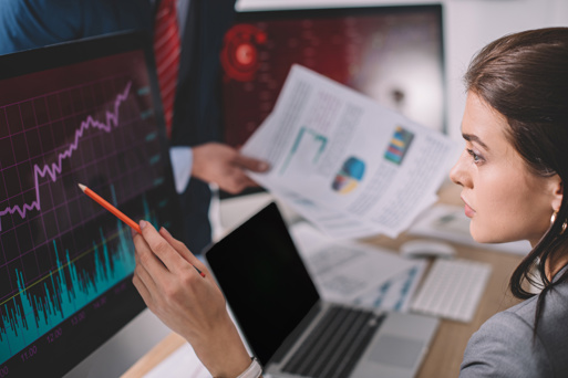 A Data Analyst closely studying a graph on a large computer screen.