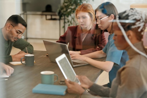 Employees working together in an office with laptops and tablets highlighting workplace access and information security risks.
