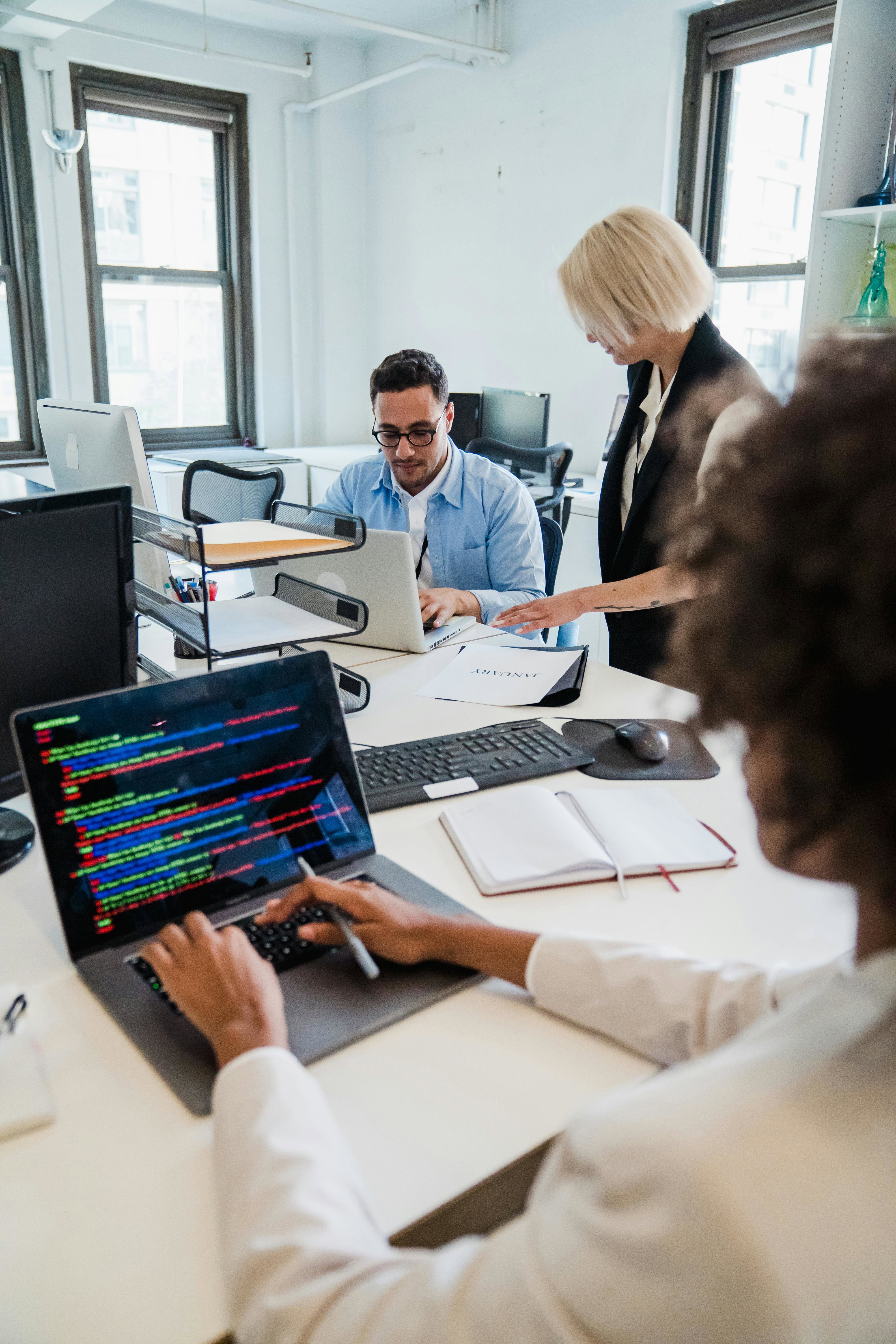Cybersecurity professionals and Project Managers working together in an office on laptops. 