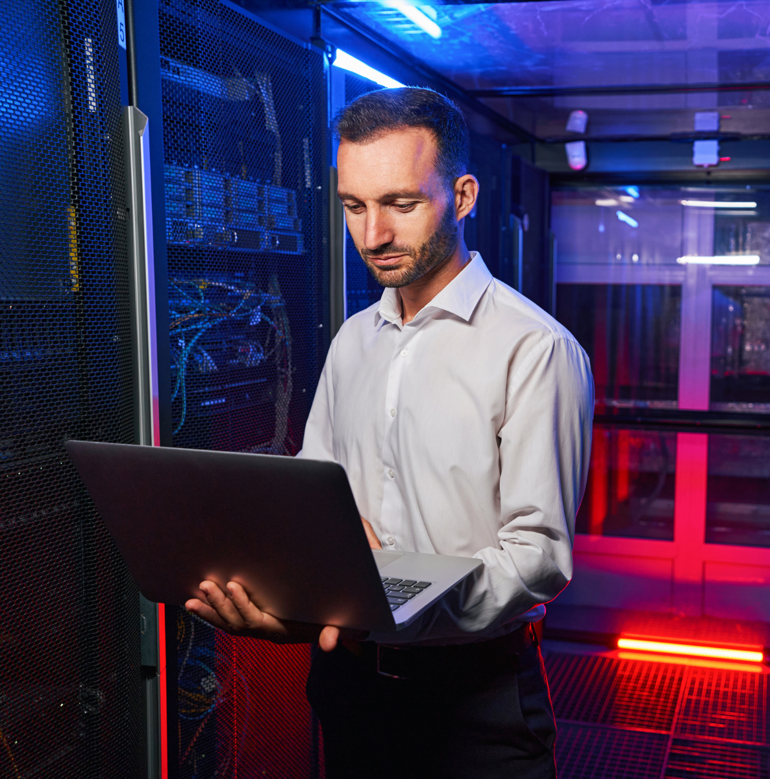 Tech professional working on a laptop in a data centre.