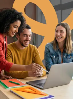 A team of people working and smiling together in an office at a laptop.