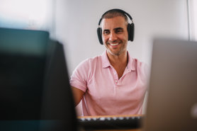 40 year old working at a computer with headphones on.