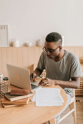 A person working on a laptop at a wooden desk.