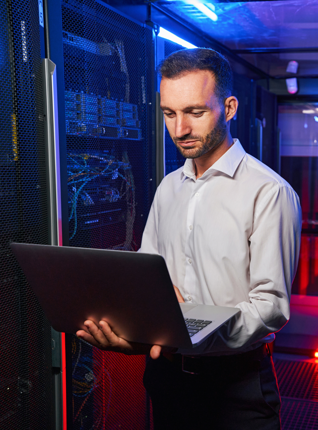 Tech professional working on a laptop in a data centre.