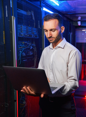 Tech professional working on a laptop in a data centre.