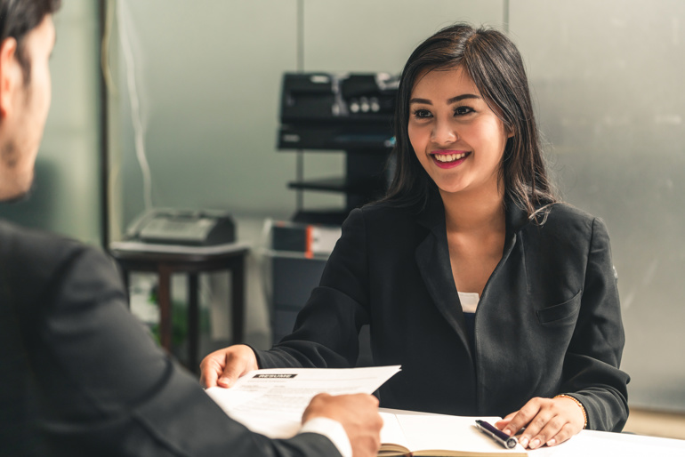 A graduate hands over a CV to a hiring manager.